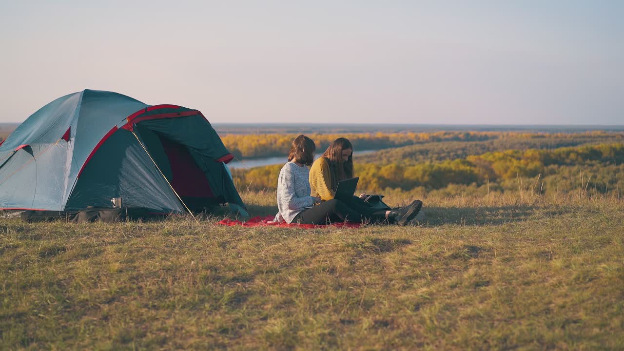 여자 관광객 들 은 텐트 에서 플레이드 에 태블릿 과 노트북 을 사용 한다