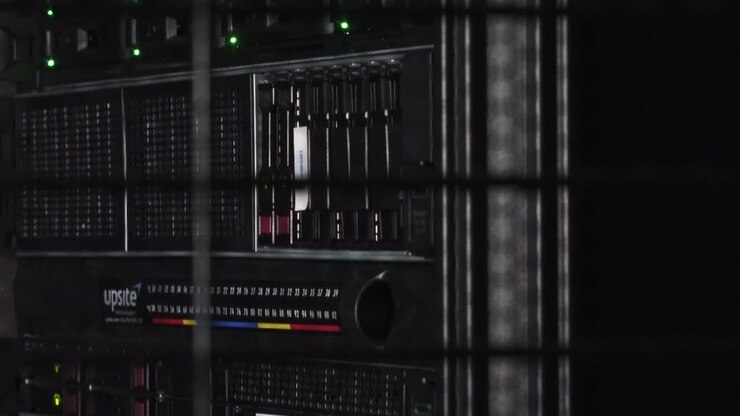 Data servers behind grid illuminated by white dim light