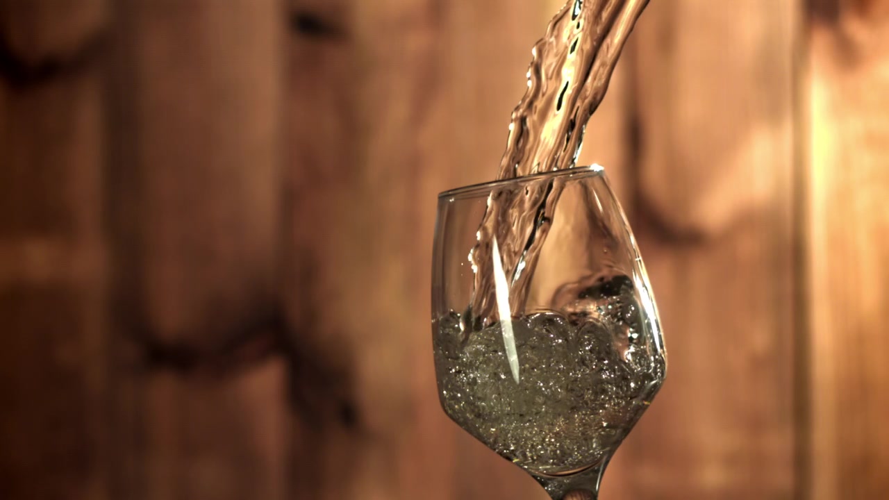 Liquido trasparente versato in un calice da vino al rallentatore