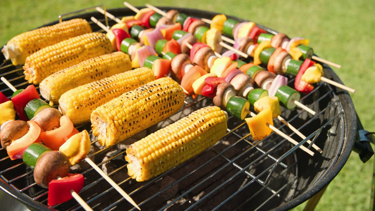 Grilling corn and vegetable skewers in garden on sunny day, enjoying barbecue