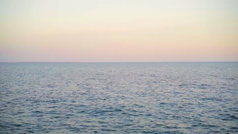 Empty-sea-horizon-viewed-from-shore-at-sunset-with-pink-and-orange-sky