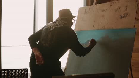 artista sénior pintando un paisaje en un estudio