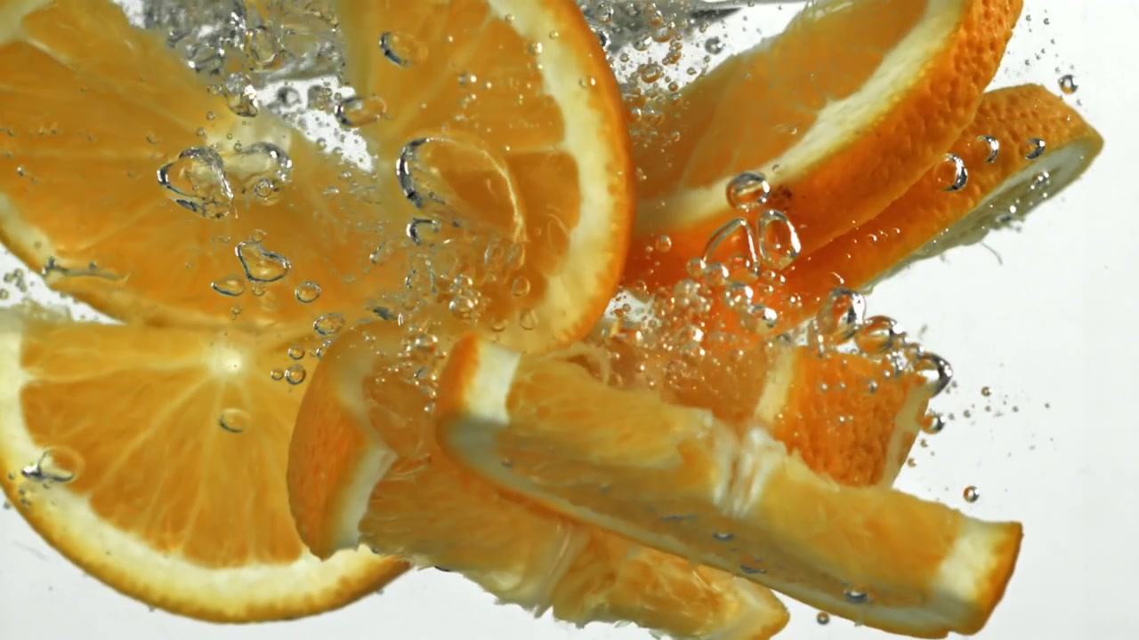Fette d'arancia fresche che si tuffano in acqua limpida con bolle