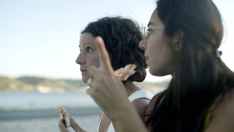 mujeres multiétnicas comiendo pizza al aire libre