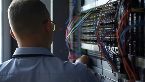 it professional working on server rack with colorful cables