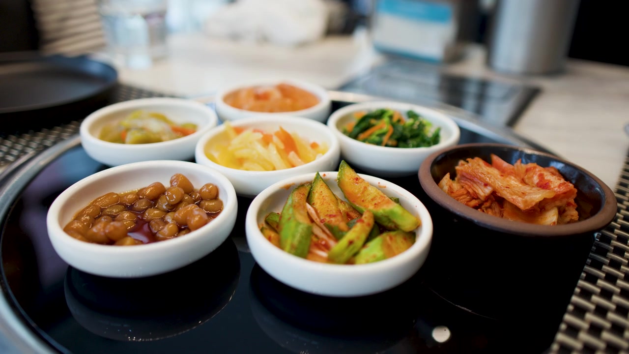 Rekaman close-up berbagai lauk Korea fermentasi termasuk kimchi dan acar timun pedas di atas meja