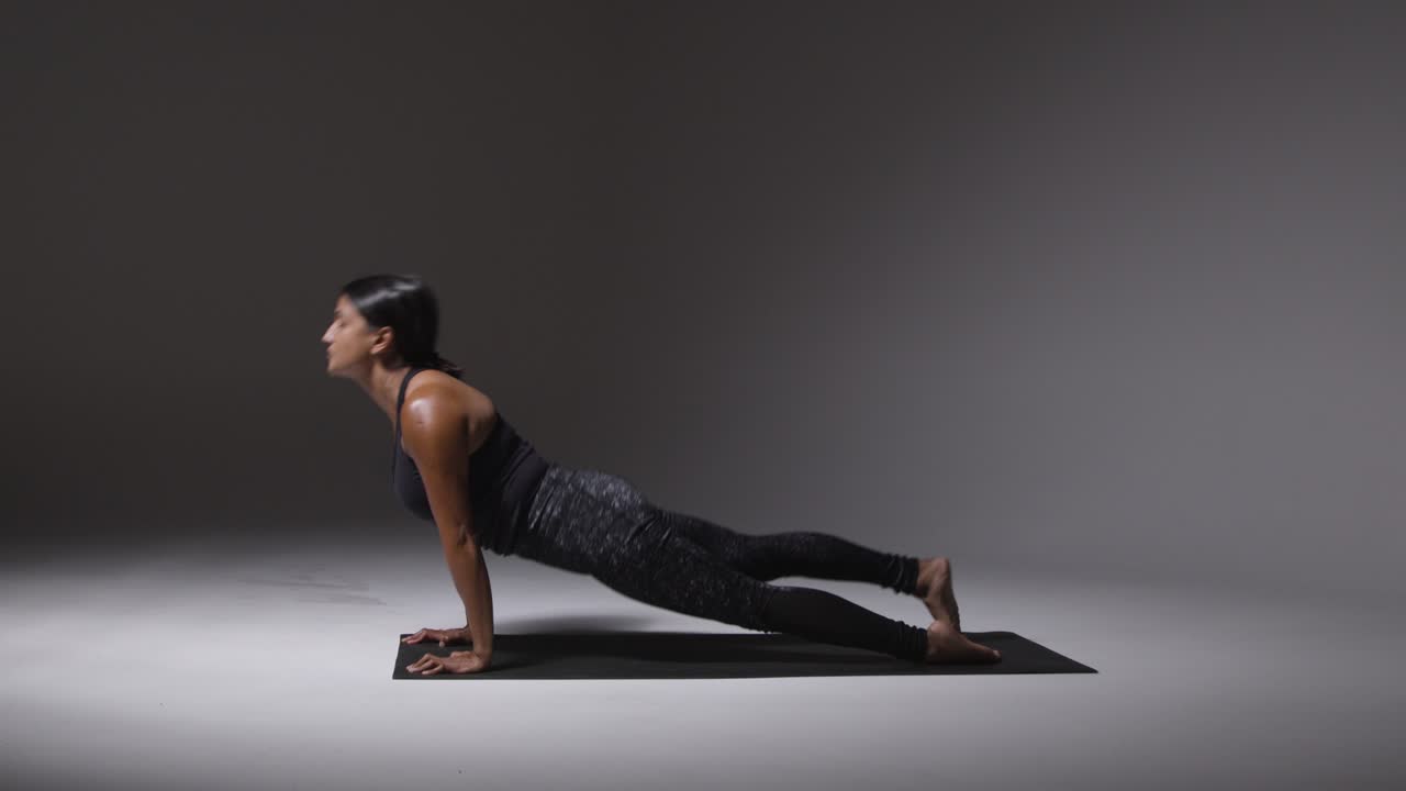 fotografía de estudio de una mujer madura con ropa de gimnasia de pie en una alfombra haciendo una variedad de ejercicios de estiramiento de pilates 1