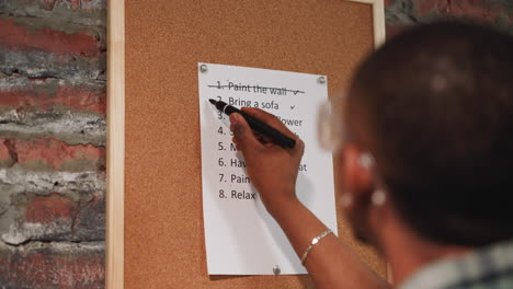 Black guy crosses out accomplished to-do list item on board
