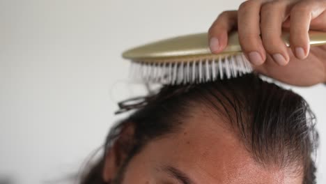 man using brush on his head with baldness, detangler