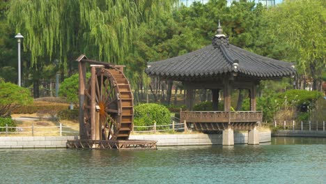 Noria-De-Madera-Tradicional-Coreana-Y-Pabellón---Pagoda-Del-área-De-Descanso-Cerca-Del-Lago-En-El-Parque-Central-De-Songdo-Incheon