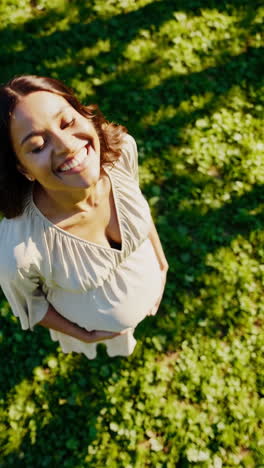 pregnant woman smiling joyfully in the sunlight in a park