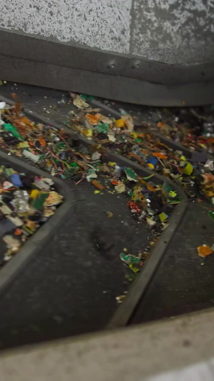 Shredded Circuit Fragments On Conveyor Belt, Multicolored Pcb Chips And Solder Flecks Sliding Between Rollers,