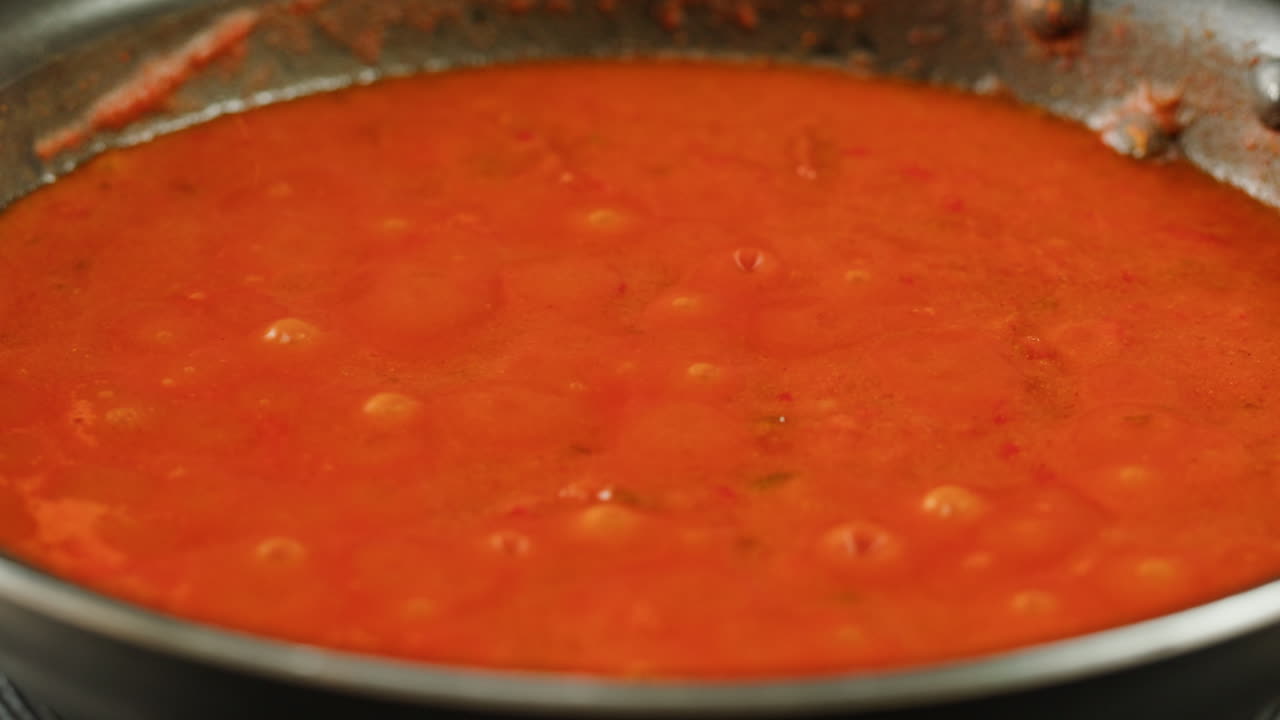 Chicken in tomato sauce is boiling on a frying pan with spices. Cooking tomato sauce curry with chicken fillet. Traditional Italian Mexican Asian dish. High quality studio shot for cafe, restaurant close up.