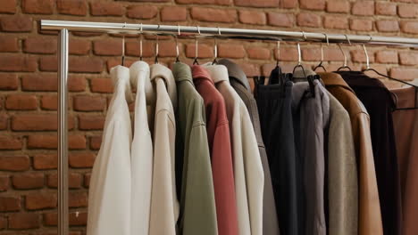 clothing on a rack in front of a brick wall