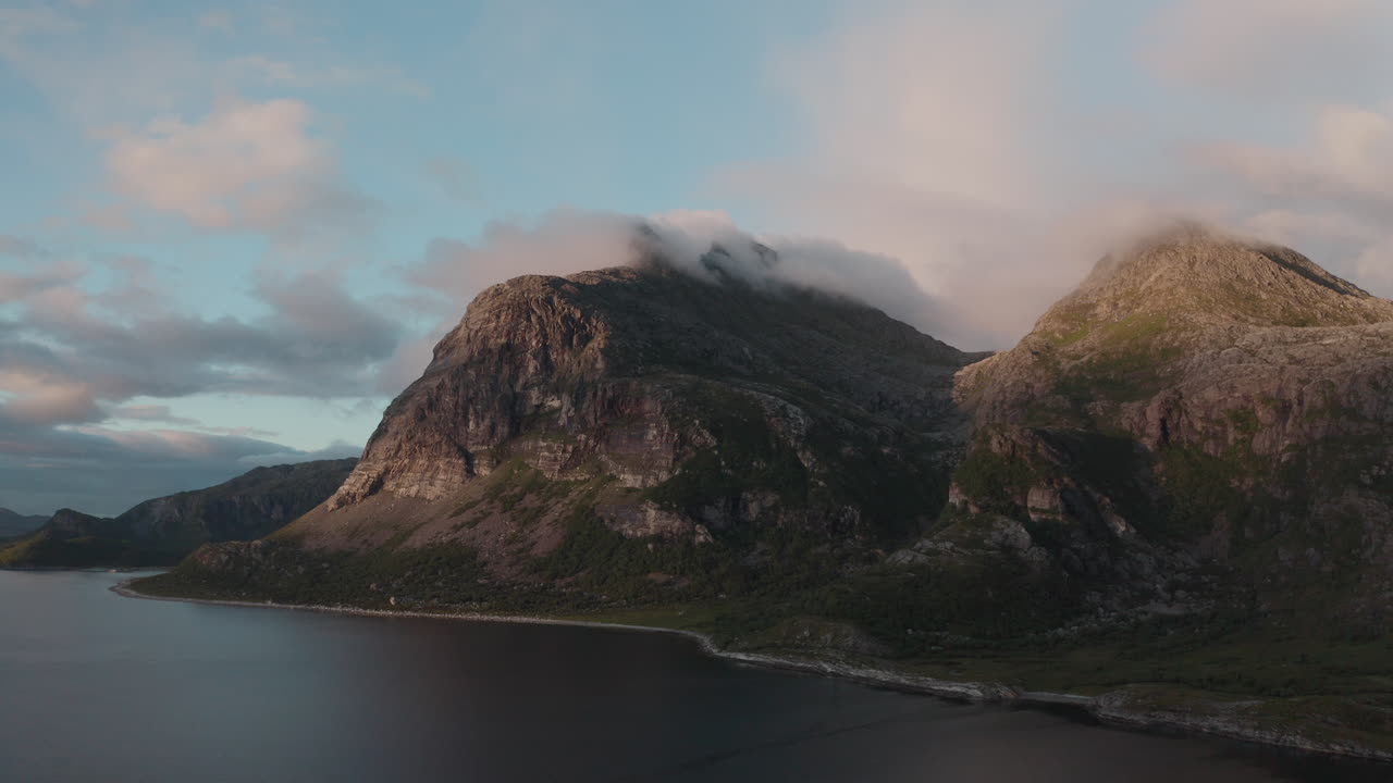 Moody drone view of Dønna’s rocky coastline and mountains in the gentle midnight sun