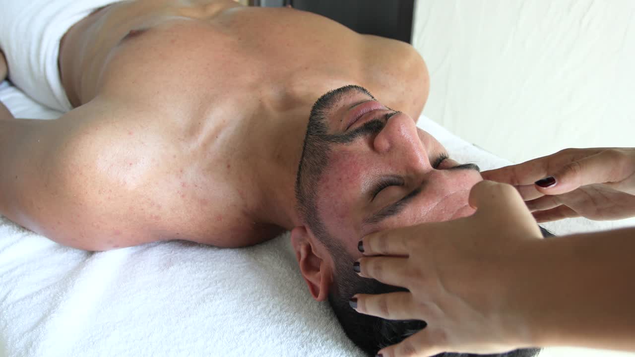 젊은 남자가 스파에서 머리 마사지를 받고 있다