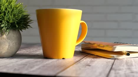 cozy workspace with yellow mug and notebook