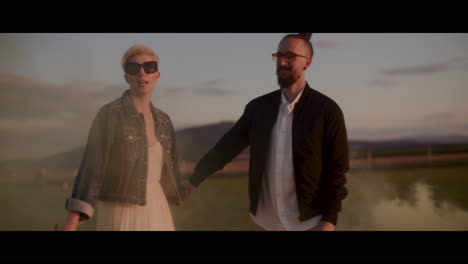 couple walking through a field at sunset