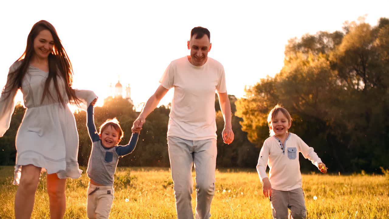 feliz familia su hombre con dos hijos caminando por el campo al atardecer en la luz del atardecer en el verano en clima cálido.