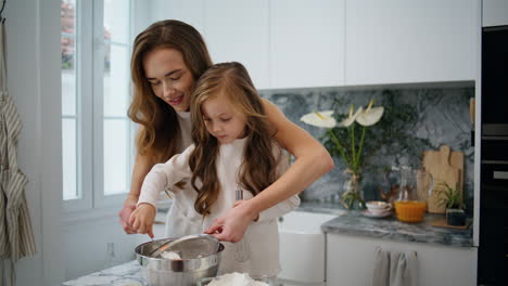 Adorable-Niño-Ayudando-A-Mamá-En-La-Cocina-De-Cerca.-Madre-Hija-Tamizando-Harina