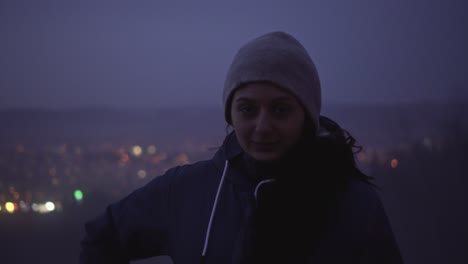 cute girl looking into camera, blurry city lights in background, portrait view with copy space