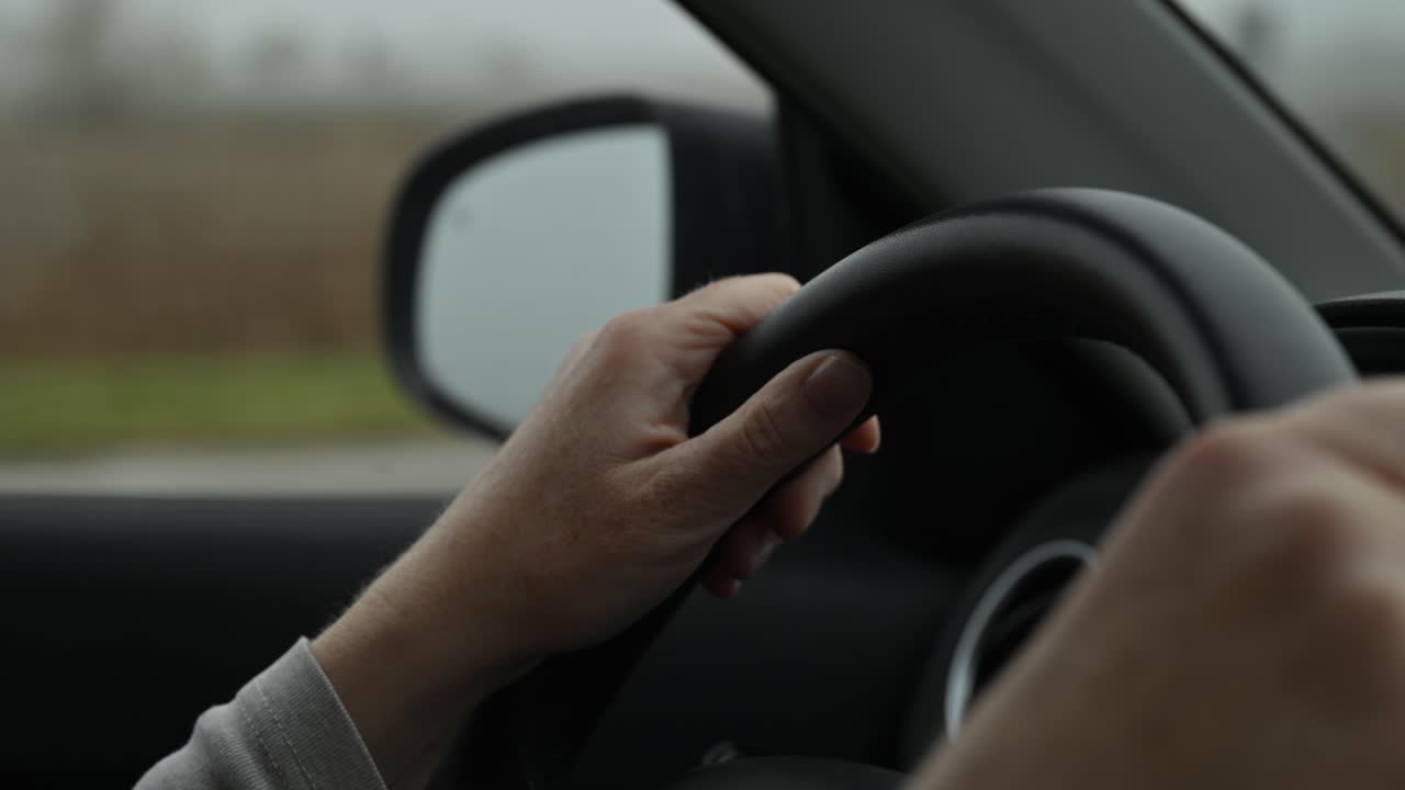 Woman’s hands holding the steering wheel during a rural drive, captured in soft natural light. Selective focus