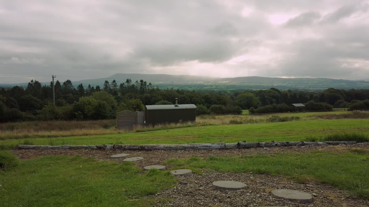 Single lodge overlooking British countryside on a cloudy day with sun rays