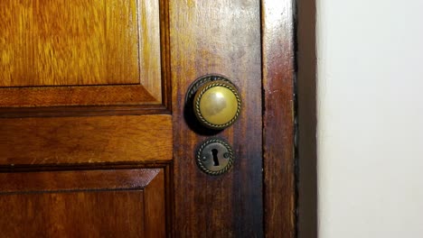 door knob turns and man with black glove opening wooden door slowly