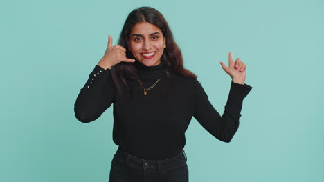 joven india mirando a la cámara haciendo un gesto telefónico como dice hola me llamas conversación
