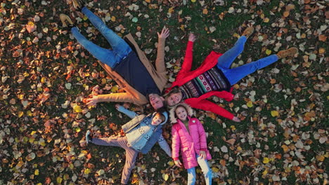 family lying in autumn leaves