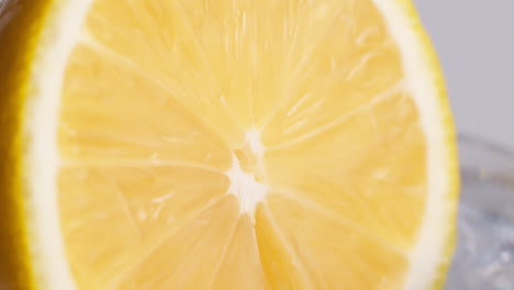 slow motion macro shot of flowing water from lemon slice on white background