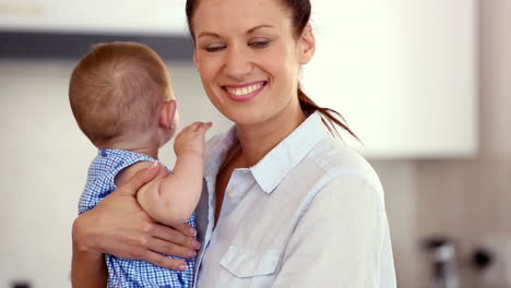 Pretty-mother-using-laptop-and-holding-baby