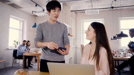 multiethnic colleagues talk in modern office. young happy asian man discussing work with beautiful caucasian girl 4k