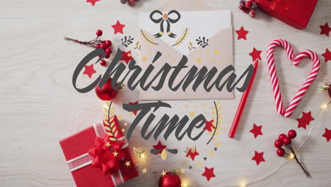 animation of christmas time text over christmas decorations, gifts, candlies on table