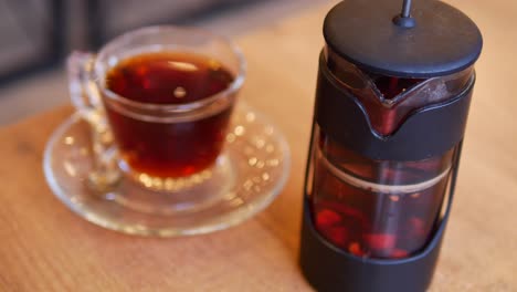 una taza de té y un infusor de té en una mesa de madera