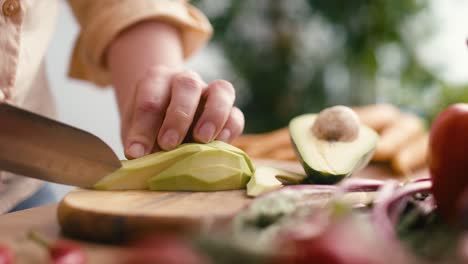 Close-up-of-hands-of-woman-cutting-avocado-at-the-kitchen.