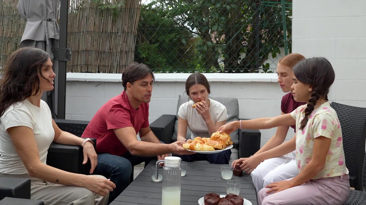 Familia disfrutando del desayuno juntos en un patio exterior.