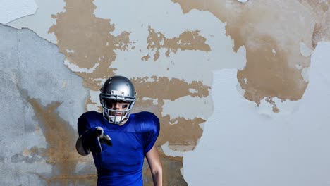 Animation-of-american-football-player-pointing-at-camera-over-distressed-wall