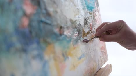 an artist in a work coat records a video blog as he paints a picture with brushes on a white canvas an artist in a work coat records a video blog as he paints a picture with brushes on a white canvas the process of creating an oil painting in the workshop