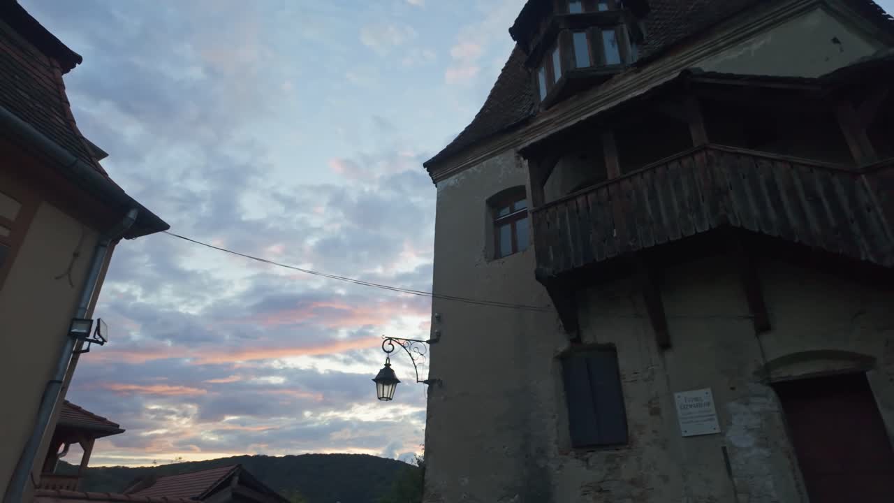 Pan shot from a local house facade towards the Bootmakers Tower during sunset in Sighișoara, Romania
