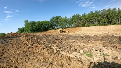 skid steer loader and bulldozer work to build side walls of a large pond at a new development site