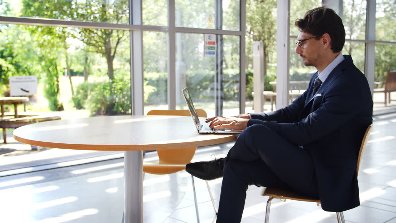 현대적 인 사무실 에서 노트북 을 사용 하고 있는 테이블 에 앉아 있는 사업가