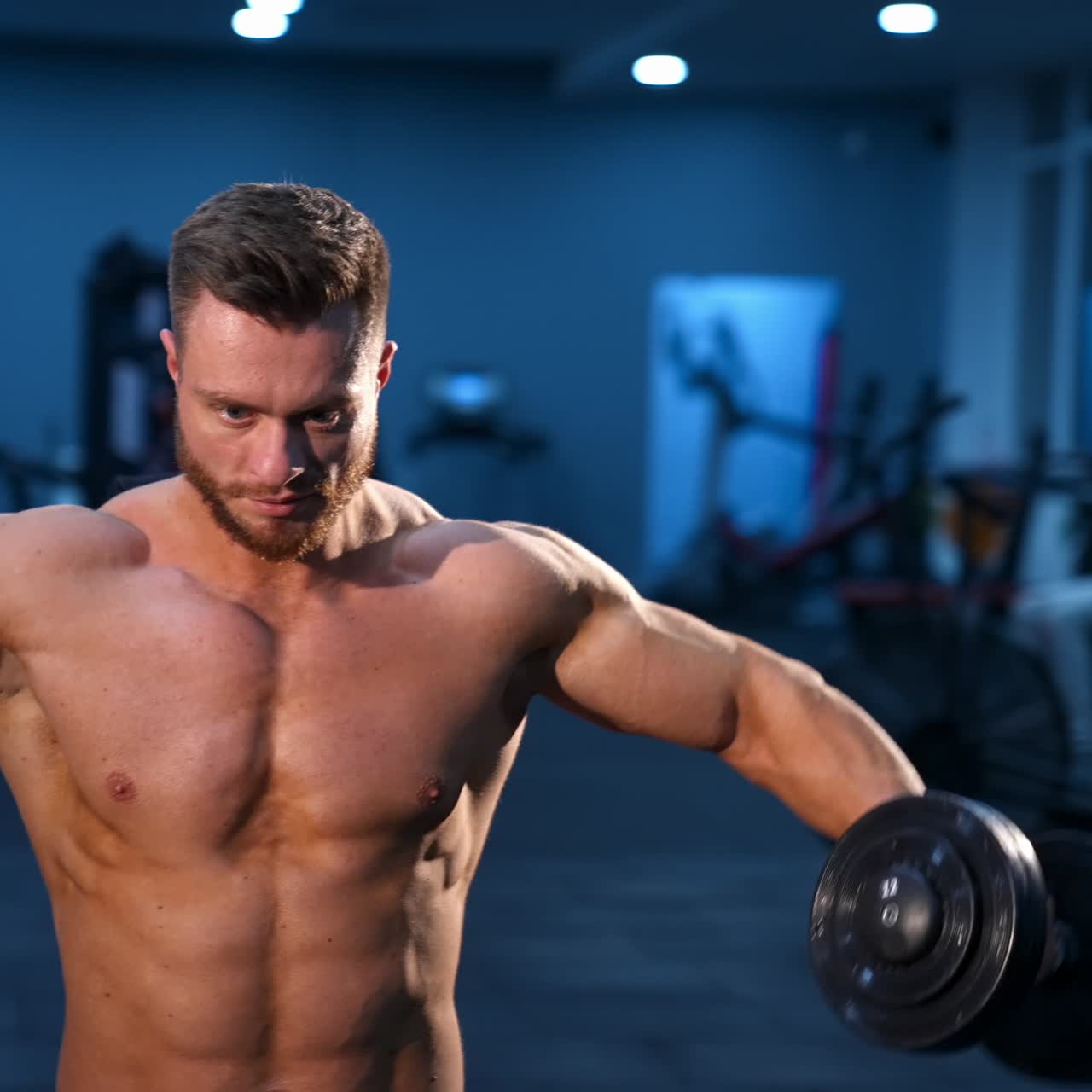 Uomo bodybuilder atletico e potente che esegue esercizi con i manubri. Corpo muscoloso e in forma su sfondo scuro di palestra.