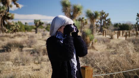 an adult woman photographer taking pictures with her old fashioned film camera and lens in a desert wildlife landscape