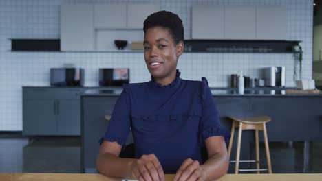 African-american-businesswoman-having-video-chat-smiling-and-talking-in-workplace-kitchen