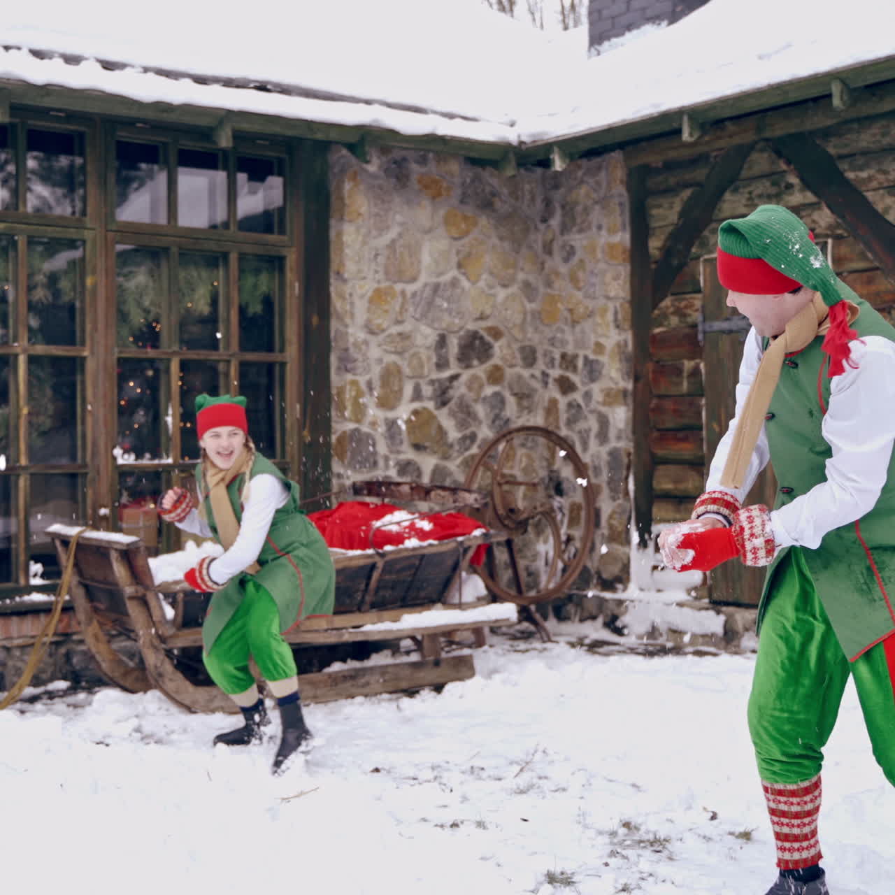 Couple of elves are playing snowballs running aroud a backyard. Holidays. Christmas eve. New year is coming. Winter landscape
