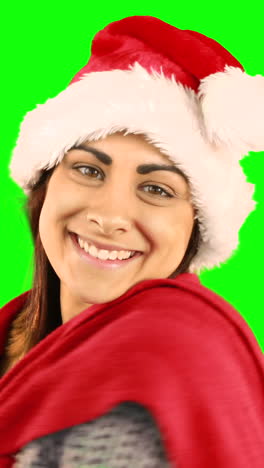una bonita morena con sombrero de santa enviando un beso en el aire a la cámara