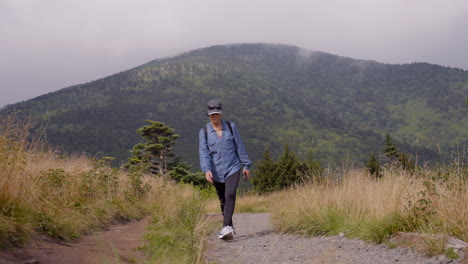 foto frontal de una mujer caminando por un sendero de montaña en un hermoso paisaje en un día nublado en tennessee