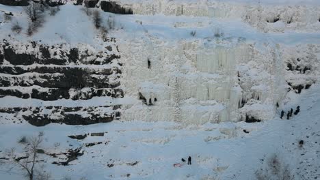 toma aérea de retroceso que muestra a un escalador de hielo en una empinada pared de montaña nevada en el cañón de provo, utah