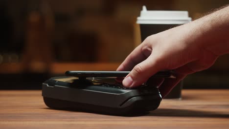 paying with smartphone close-up. cashless shopping in restaurant or cafe. buying coffee using touch-free and contactless payment concept. nfc technology and bank terminal.